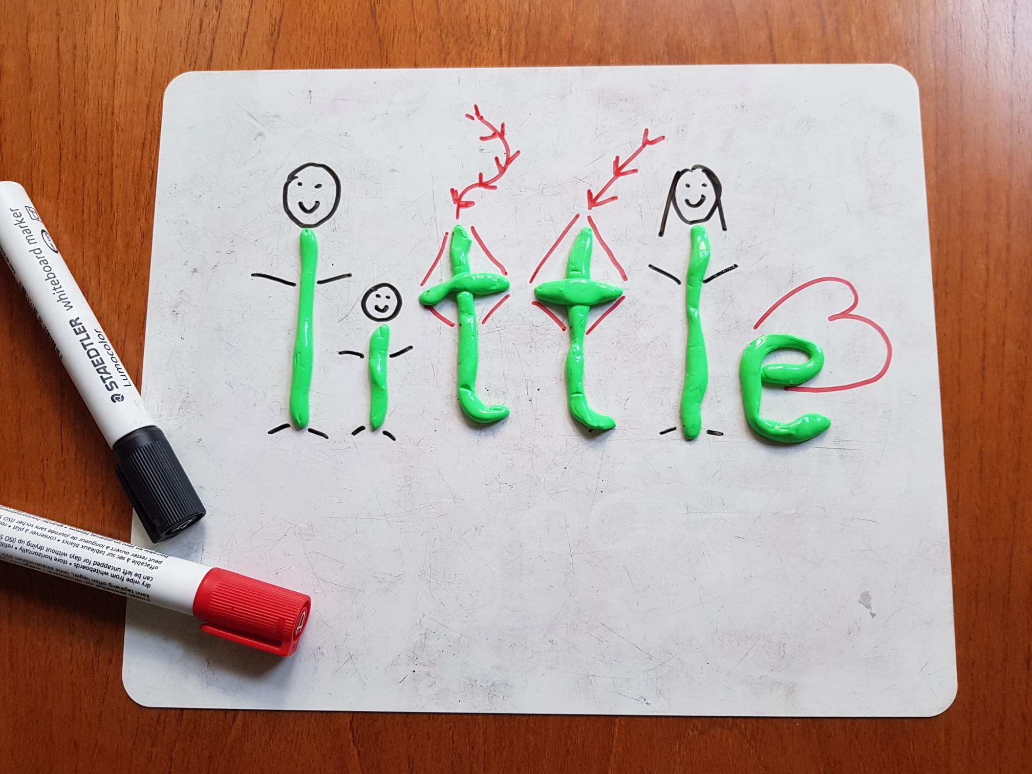 The word 'little' spelled in green modelling clay on a whiteboard